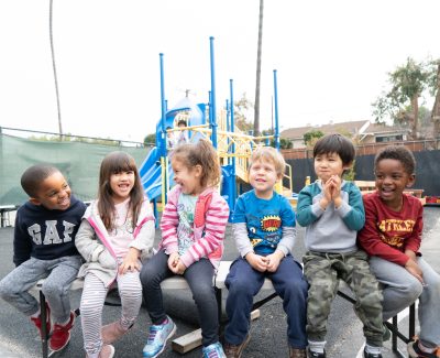 Preschool students on playground laughing and smiling
